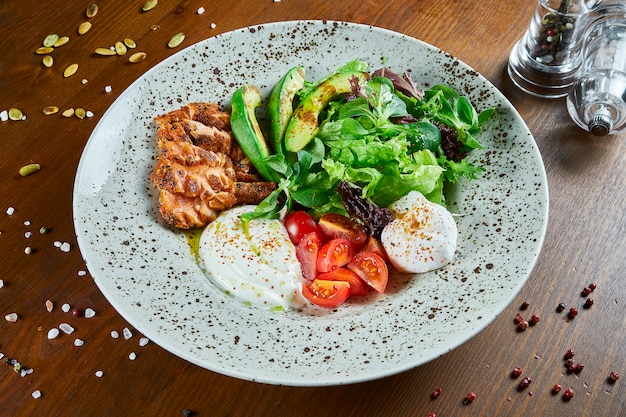 Insalata Gourmet Con Salmone Arrosto Salsa Di Panna Avocado Spinaci Lattuga Mozzarella E Pomodorini Sul Tavolo Di Legno Insalata Di Mare Deliziosa Avvicinamento Foto Premium