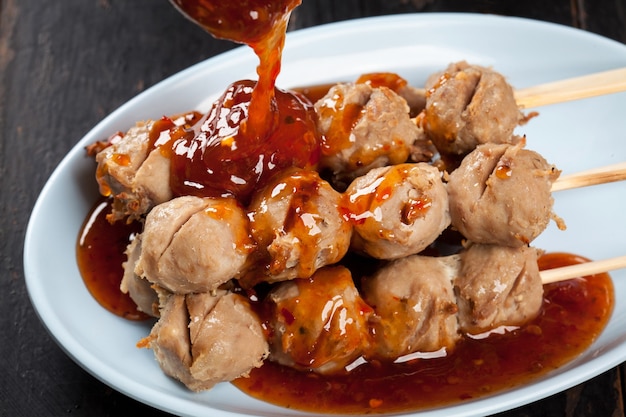 Polpette Di Carne Alla Griglia Spiedino Di Bambu Sul Piatto Bianco Con Salsa Piccante Sul Tavolo Di Legno Tendine Di Polpette Di Manzo Alla Griglia Cibo Di Strada Della Thailandia Foto