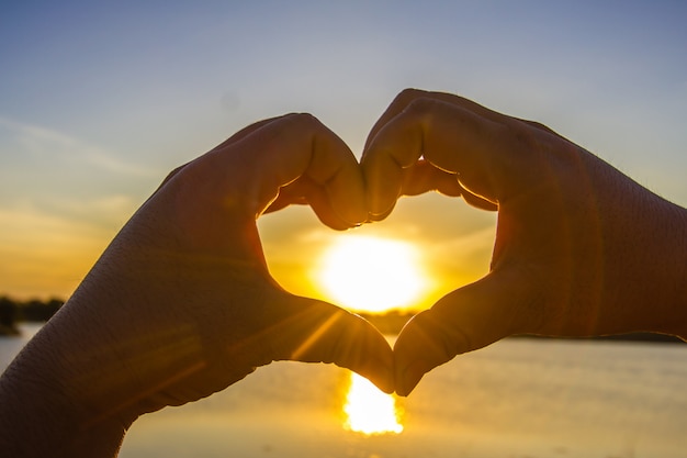 Mani Che Formano La Forma Di Un Cuore Con Il Sole Al Centro Foto Premium