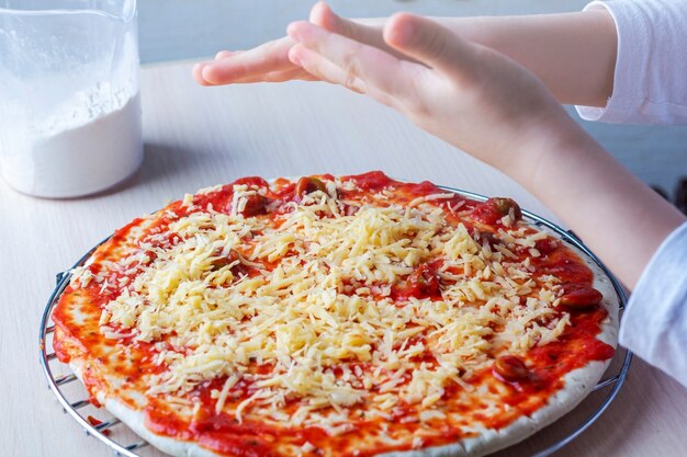 Mani Del Bambino Cospargere Di Formaggio Sulla Pasta Della Pizza Foto Premium