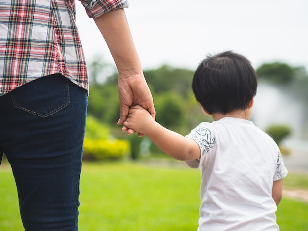 Madre E Figlia Che Si Tengono Per Mano Che Camminano Nel Parco Concetto Di Famiglia Di Bambino E Mamma Foto Premium