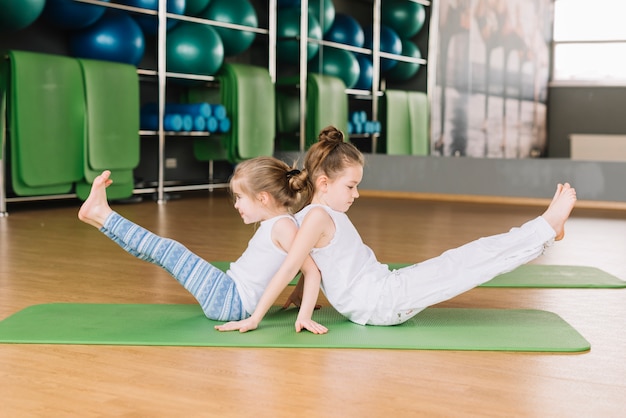 Una Vista Laterale Di Due Piccole Bambine Che Fanno Esercizi Di Yoga Foto Premium