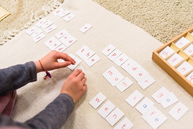 Uno Studente Di Una Scuola Montessori Che Usa Le Carte Con Le Lettere Per Comporre Parole E Frasi Su Una Stuoia Foto Premium