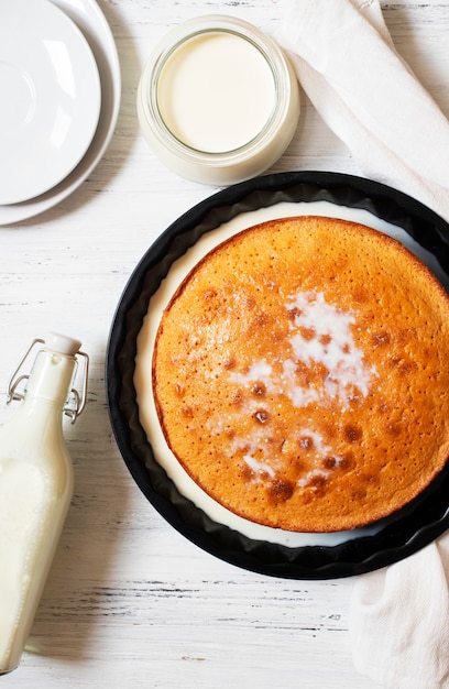 Dessert Tradizionale Three Milk Tres Leches O Trilece Il Dessert E Servito Su Un Tavolo Di Legno Bianco Con Latte In Una Bottiglia E Una Tazza Con Piatti Bianchi Vista Dall Alto