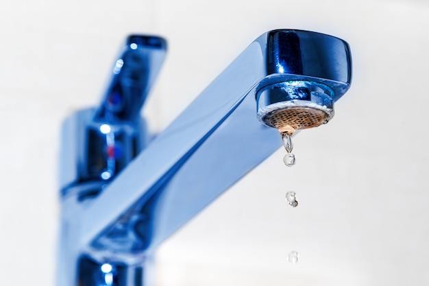 Gocce d'acqua gocciolano dal rubinetto cromato nel lavello della cucina o nel bagno. il concetto dell'idea di risparmiare acqua. Foto Premium