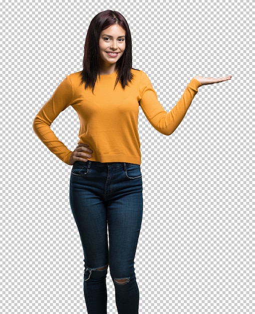 Giovane donna graziosa che tiene qualcosa con le mani, mostrando un prodotto, sorridente e allegro, offrendo un oggetto immaginario Psd Premium