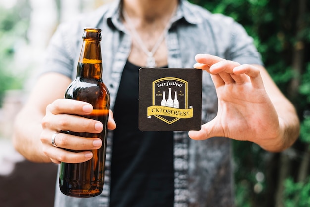 Hombre sujetando la botella de cerveza y posavasos PSD gratuito