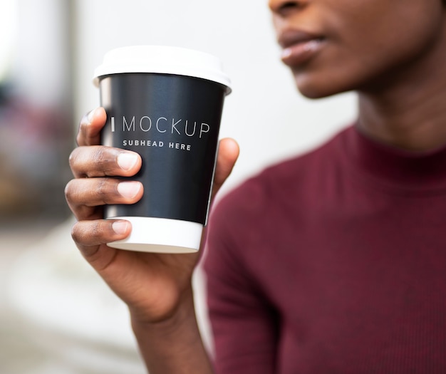 Mujer tomando café en una taza de papel maqueta PSD Premium