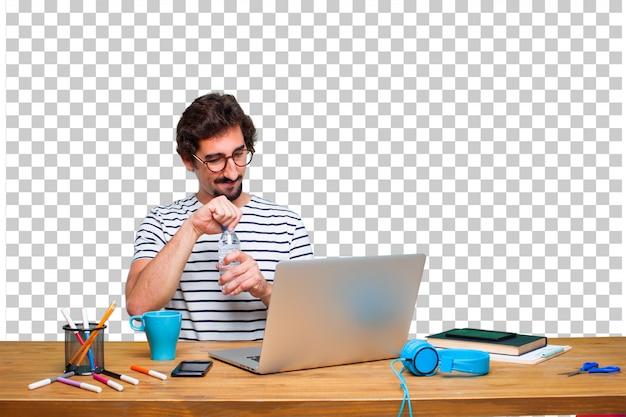 Jeune graphiste fou sur un bureau avec un ordinateur portable et une bouteille d'eau PSD Premium