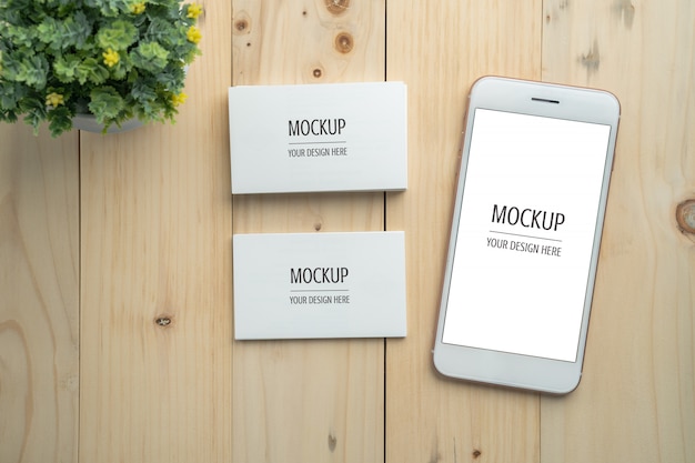 Maquette de carte de visite smartphone et blanc écran blanc sur table en bois PSD Premium