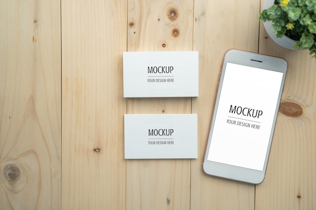 Maquette de carte de visite smartphone et blanc écran blanc sur table en bois PSD Premium