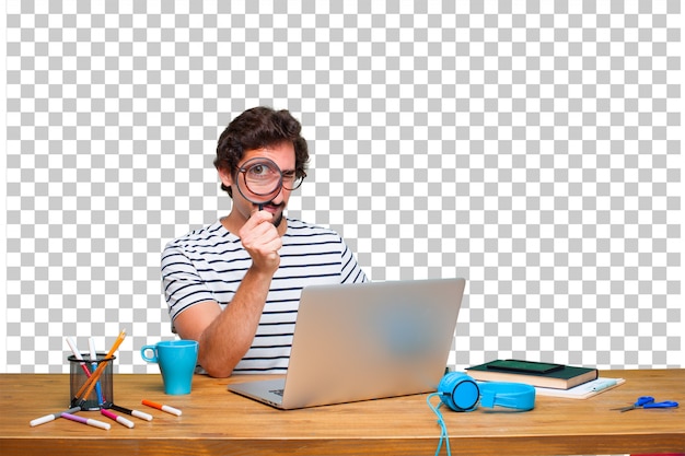 Jovem designer gráfico louco em uma mesa com um laptop e com uma lupa Psd Premium