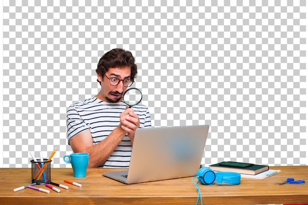 Jovem designer gráfico louco em uma mesa com um laptop e com uma lupa Psd Premium