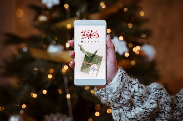 Maquete de venda de natal com a mão segurando o smartphone Psd grátis