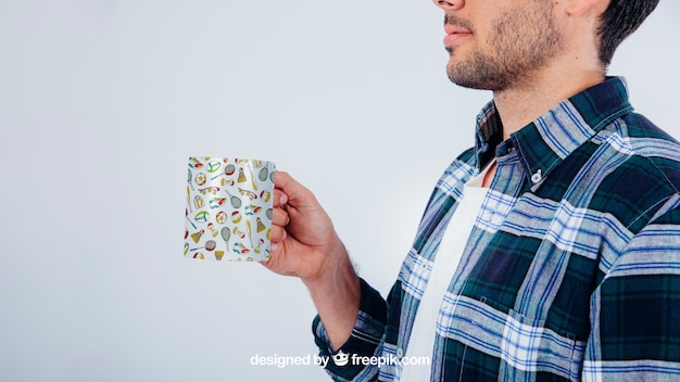Download Mock up design com jovem homem segurando caneca de café | PSD Grátis