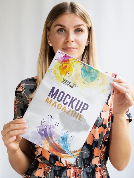 Mulher olhando para a câmera e mostrando uma revista mock up Psd grátis