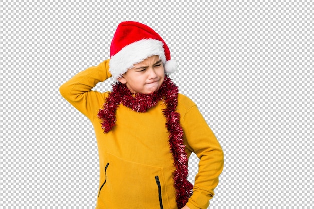 O rapaz pequeno que comemora o dia de natal que veste um chapéu de santa isolou o toque na parte de trás da cabeça, pensando e fazendo uma escolha. Psd Premium
