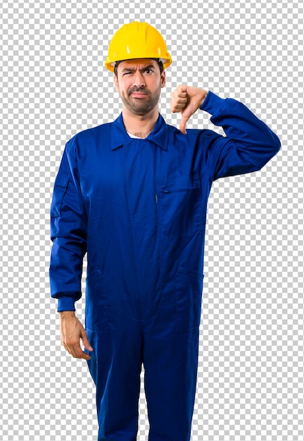 O trabalhador novo com o capacete que mostra o polegar assina para baixo com expressão negativa. expressão triste Psd Premium