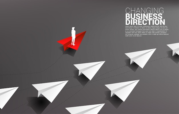 Silhouette d'homme d'affaires debout sur un avion en papier origami rouge est la direction à part du groupe de blanc. business concept de perturbation et marketing de niche Vecteur Premium
