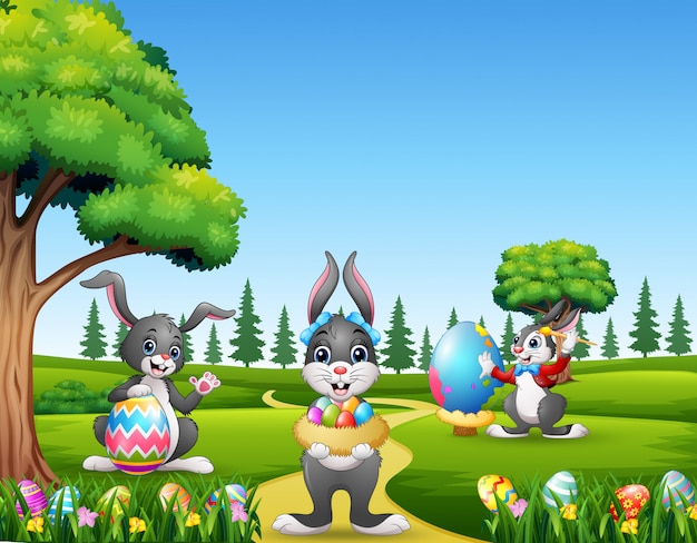 Felices conejitos de pascua sosteniendo y pintando huevos Vector Premium