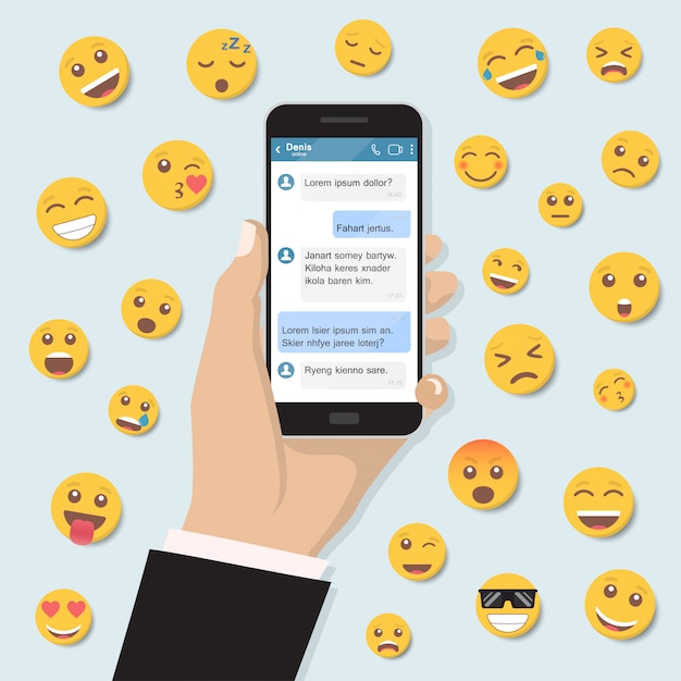 Mão segurando o smartphone com mensagens de bate-papo e emoticon em um design plano Vetor Premium