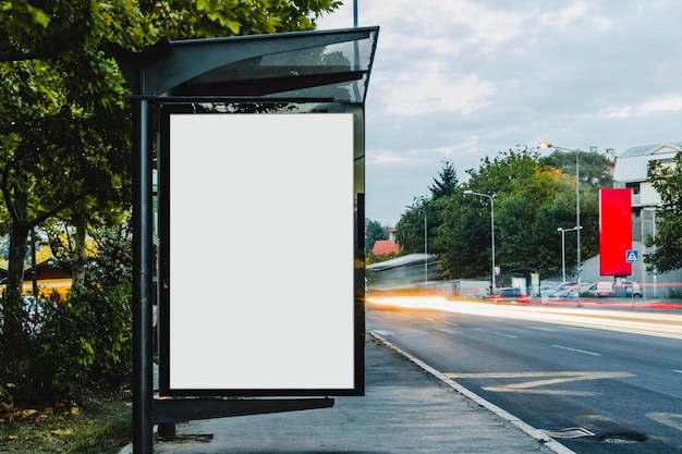Aanplakbord bij bushalteschuilplaats met vaag spoorlicht Gratis Foto