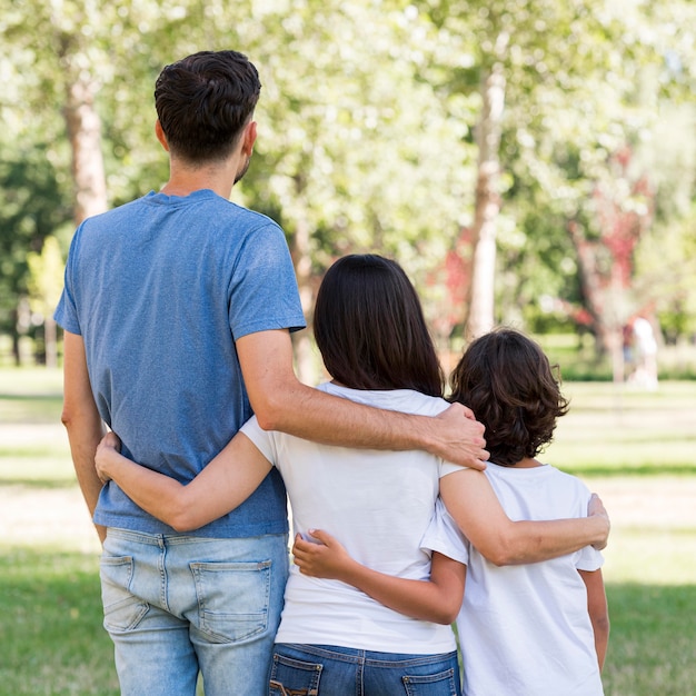 Achteraanzicht van gezin  met ouders en  kind  omarmd 