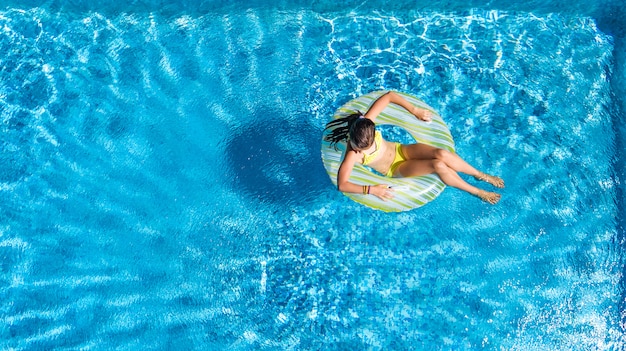 aantrekkelijk zegen Vormen Actief meisje in zwembad luchtfoto bovenaanzicht van bovenaf, kind zwemt op  opblaasbare ring donut | Premium Foto