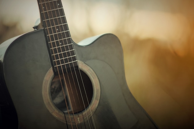 Akoestische gitaar in een weide op zonsondergang landschap-achtergrond Gratis Foto