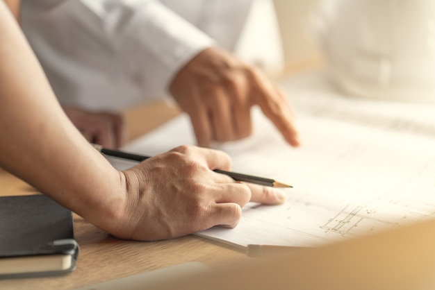 Architect en ingenieur werkt tekendocument over projectplanning en voortgang van het werkschema op de bouwplaats voor woningbouw Premium Foto