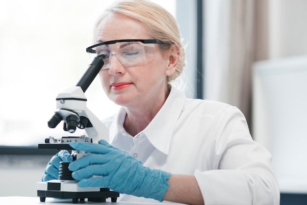 Arts die met een microscoop analyseert Gratis Foto