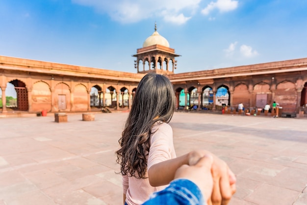 Aziatische jonge vrouwentoerist die man leiden in de rode jama mosque in oud delhi, india. samen reizen. volg mij. Premium Foto