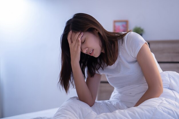 Aziatische vrouw heeft hoofdpijn in de ochtend op het bed Premium Foto