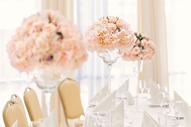 Bediende tafel voor een gebeurtenis diner met bestek en glazen, versierd met bloemige composities in vazen. Premium Foto