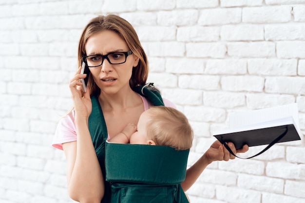 Bedrijfsvrouwen sprekende telefoon en pasgeboren houden. Premium Foto
