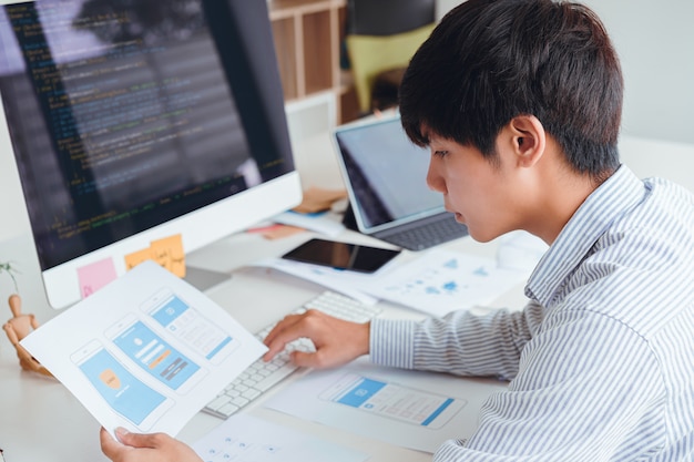 Bijgesneden opname van front-up ux ui front-end ontwerpers die een programmering en codering van mobiele applicaties ontwikkelen van prototype en draadframe-lay-out. mobiele applicatie ontwikkelaar werkplekconcept. Premium Foto