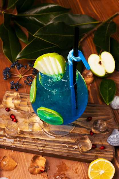 Blauwe lagunecocktail met citroenplakken in glas op houten lijst Gratis Foto