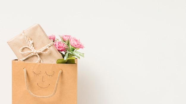 Bloemboeket en verpakte giftdoos in document zak met hand getrokken die gezicht op witte achtergrond wordt geïsoleerd Gratis Foto