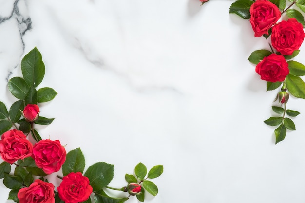 Bloemenkader met rozenknoppen en groene bladeren op marmeren achtergrond Premium Foto