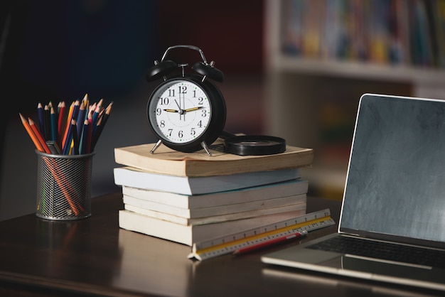 Boek, laptop, potlood, klok op houten tafel in bibliotheek, onderwijs leren concept Gratis Foto