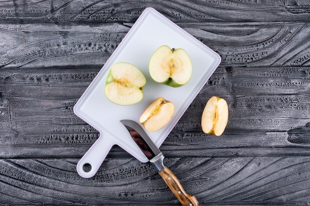 Bovenaanzicht groene appels gesneden met mes op plastic bord op grijze