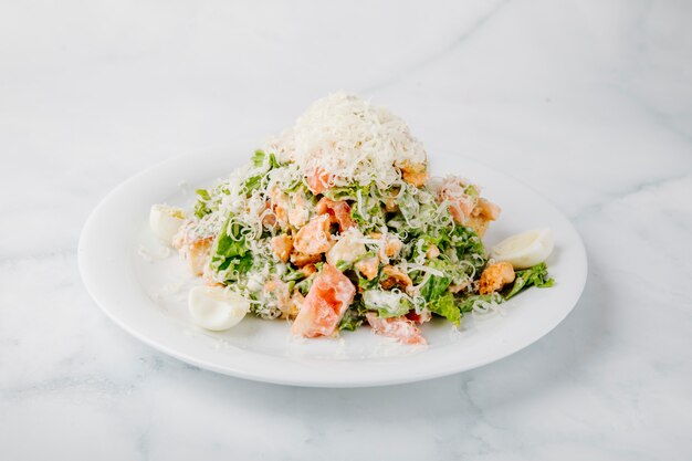 Caesarsalade met gemengde ingrediënten en gehakte kaas op de bovenkant op witte achtergrond. Gratis Foto
