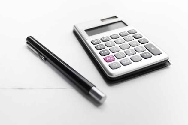 Calculator met een pen en document nota met geïsoleerd schuldwoord Premium Foto