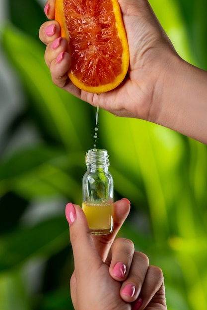 Close-up: een vrouwelijke hand drukt grapefruitsap in een glazen fles Premium Foto