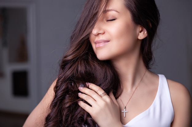 Close-up mooi donkerbruin meisje met lang haar in zilveren juwelenoorringen, ringen, armband, ketting, halsband. Premium Foto