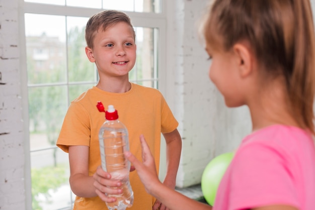Close-up van een jongen die waterfles geeft aan zijn vriend Gratis Foto
