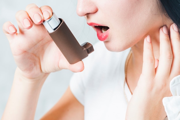 Close-up van een vrouw met behulp van astma-inhalator Gratis Foto