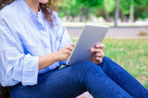 Close-up van vrouw die digitale tablet in de zomerpark gebruiken Gratis Foto