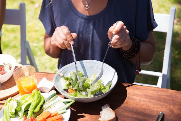 Close-up van vrouw die salade eet bij lijst in openlucht Gratis Foto