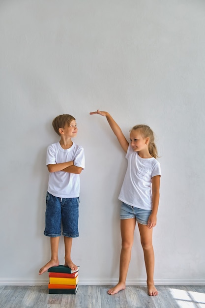 agentschap naast Niet verwacht Coole kinderen, kleine jongen en meisje meten hun lengte en vergelijken,  veel plezier bij de witte muur | Premium Foto